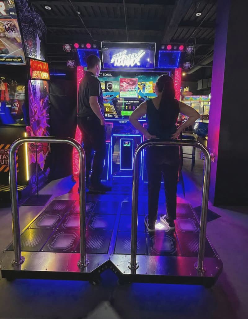 A couple playing a neon-lit dance arcade game together