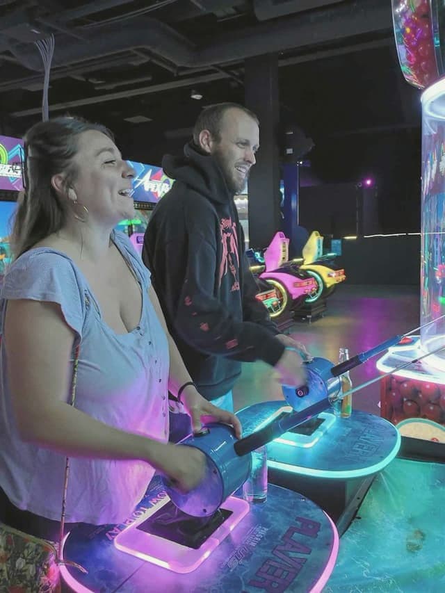 A couple laughing together over an arcade game on a date night