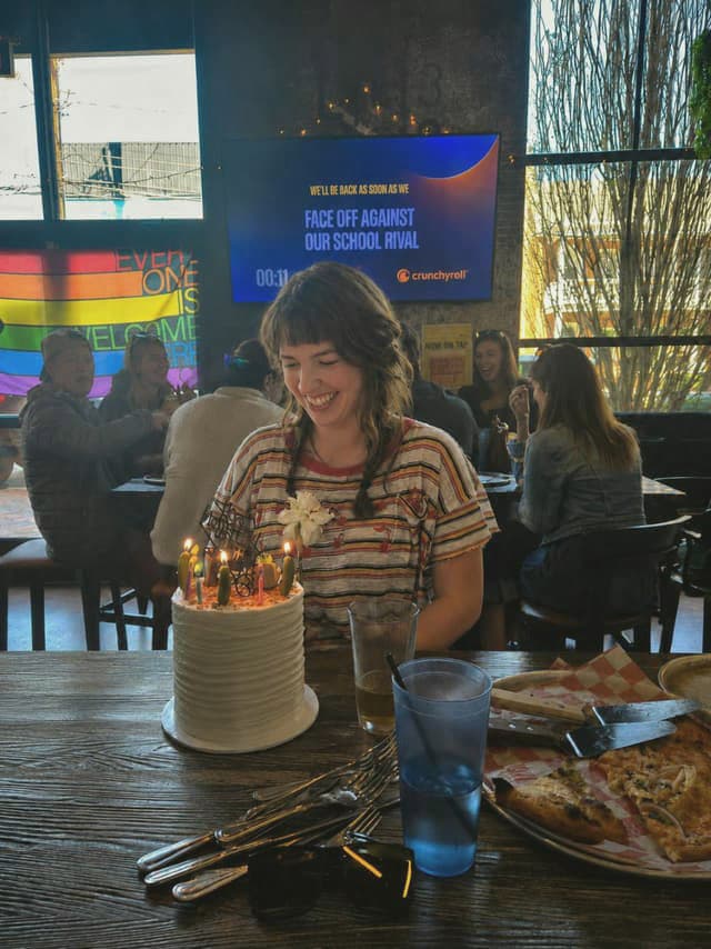 Smiling at a birthday cake with lit candles