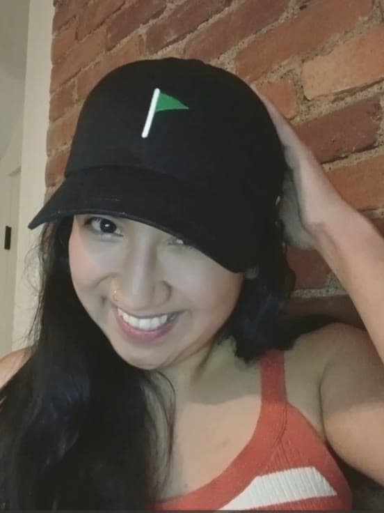 Emi Dawson, founder of Big Moments Company, in a black cap with the company green flag on it