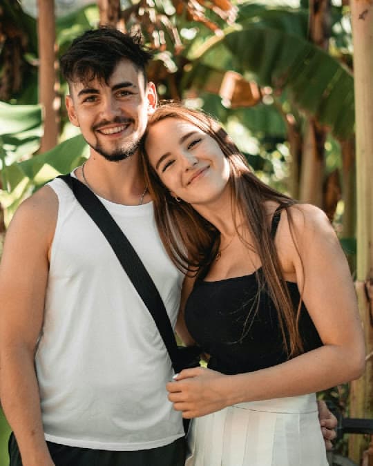 A couple on a tropical getaway, smiling together among banana-leaf greenery