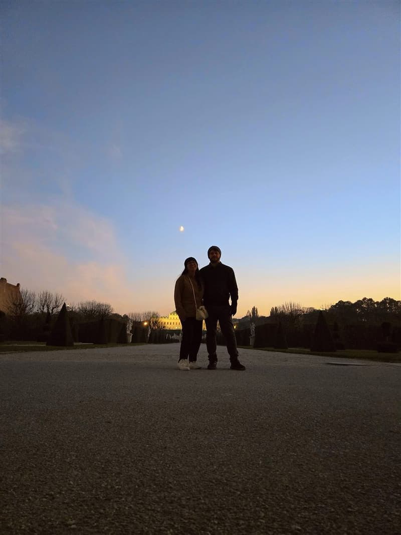 A couple at dusk in a palace garden with the moon overhead