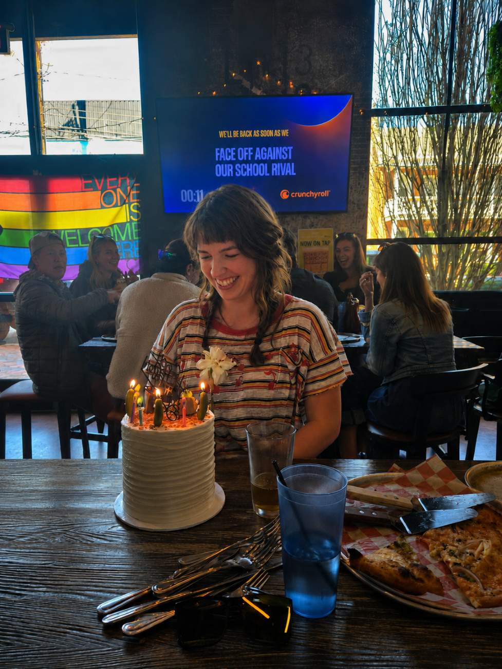 A woman smiling at her birthday cake with lit candles